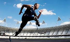 The Wondrous. Action photo of male runner with bilateral high-tech racing prosthesis. Camera angle from below invites viewer to look up at athlete.