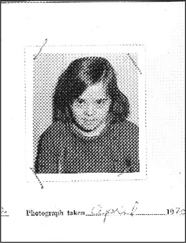 A black and white intake photograph is affixed to the
        centre of a white paper, tape angled at its corners.