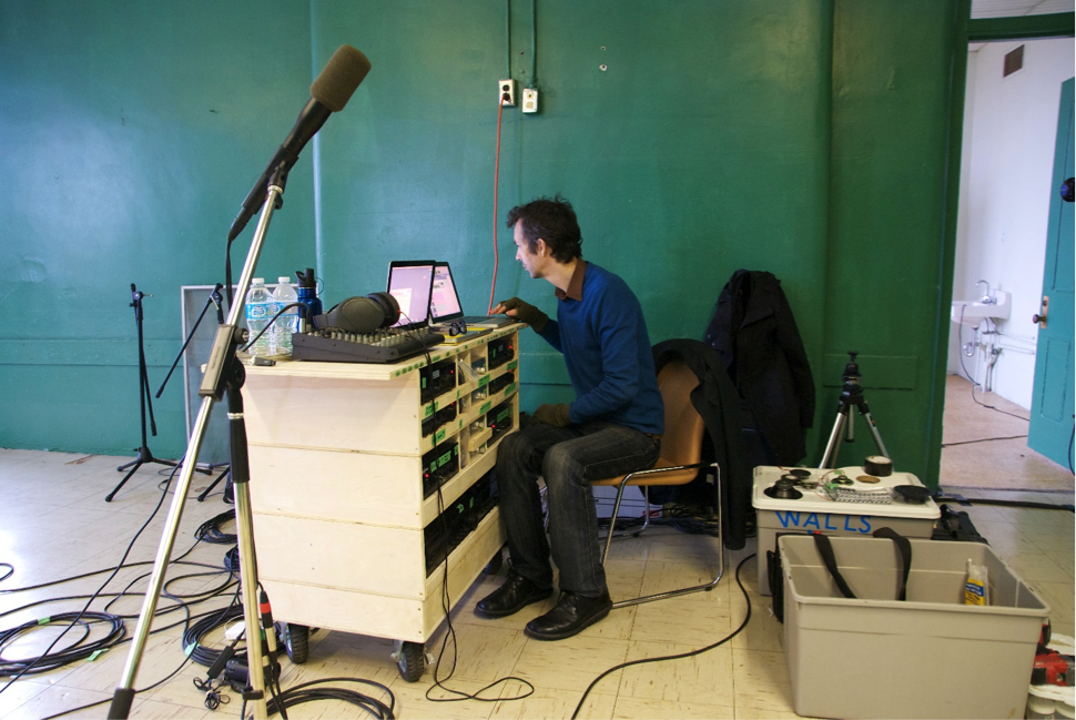 Christof Migone sits at a sound station, his body turned
          away from the camera.