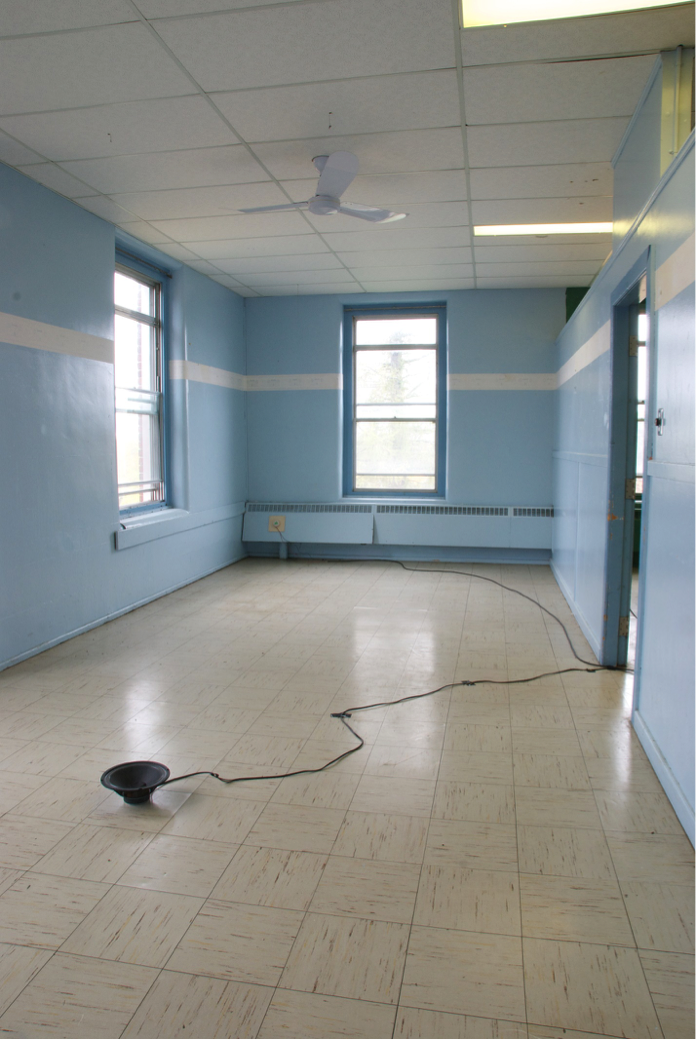 A long empty room with powder blue walls and a thick
          white painted stripe painted more than half way up the wall.